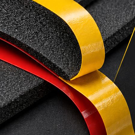 Rubans adhésifs jaune et rouge posés sur des plaques de mousse noire